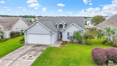 Traditional-style home featuring a front lawn, driveway, a shingled roof, a garage, and a residential view