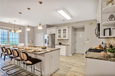 Kitchen featuring appliances with stainless steel finishes, a chandelier, tasteful backsplash, glass insert cabinets, and white cabinetry