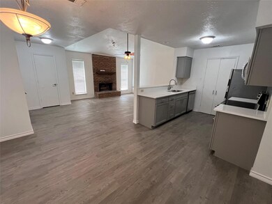 Kitchen with a large fireplace, dark wood-type flo