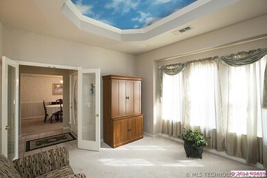 Carpeted living room or office off entry hall is spacious and light.  Glass French doors provide privacy.  Trompe-L'oeil painting on trayed ceiling for added interest.
