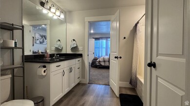 Bathroom with wood finished floors, vanity, ensuite bath, and shower / bathtub combination with curtain