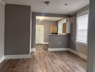 Empty room with a smoke detector, plenty of natural light, wood finished floors, and a textured ceiling