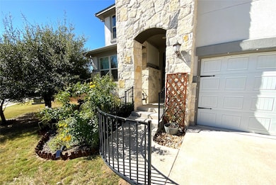 Entrance to property featuring stone siding, a garage, a yard, and stucco siding