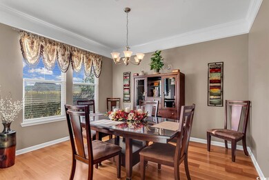 Dining area with light hardwood / wood-style flooring, ornamental molding, and a notable chandelier