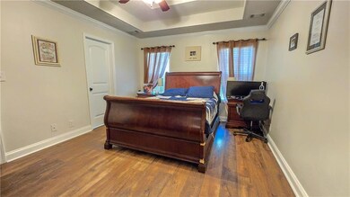 Bedroom with a tray ceiling, wood finished floors,