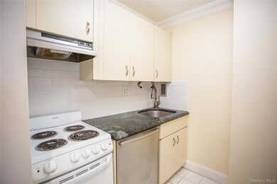 Kitchen featuring white electric range oven, tasteful backsplash, ventilation hood, stainless steel dishwasher, and light tile patterned floors
