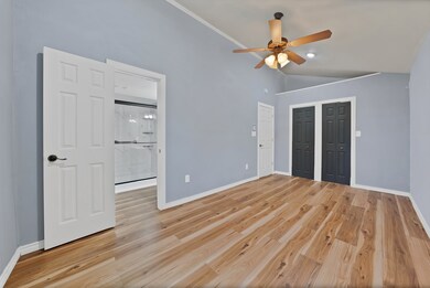 Unfurnished bedroom featuring light wood-style floors, ensuite bath, high vaulted ceiling, ceiling fan, and a closet