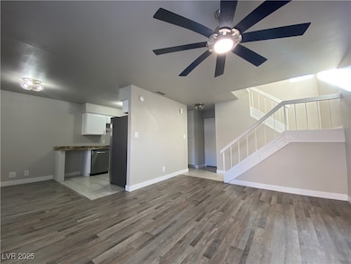 Unfurnished living room featuring stairway, light wood-type flooring, and a ceiling fan
