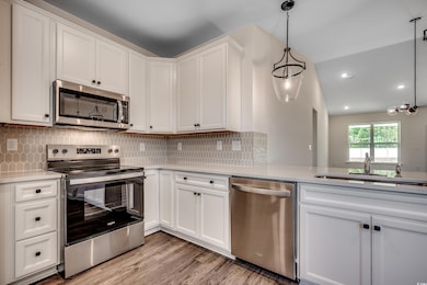 Kitchen featuring stainless steel appliances, a sink, light countertops, white cabinets, and recessed lighting