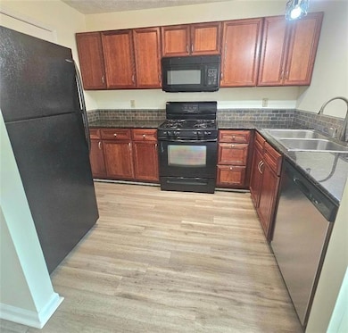 Kitchen featuring a sink, black appliances, dark c