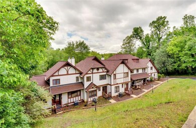 View of front facade featuring a chimney, stucco siding, view of wooded area, roof with shingles, and a front lawn