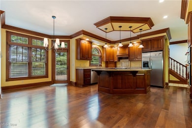 Kitchen with a kitchen bar, stainless steel appliances, dark wood-style floors, a chandelier, and a kitchen island