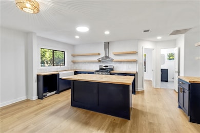 Kitchen with butcher block counters, open shelves, a kitchen island, backsplash, and light wood-style floors