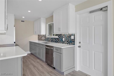 Kitchen featuring light stone counters, gray cabinetry, white cabinets, and recessed lighting