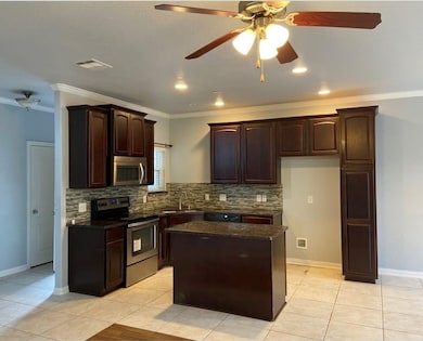 Kitchen featuring a ceiling fan, appliances with stainless steel finishes, light tile patterned floors, dark brown cabinetry, and dark stone counters