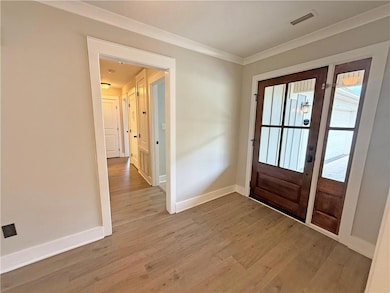 Foyer featuring light wood-style floors and crown molding
