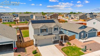 View of front facade featuring a residential view, driveway, a shingled roof, solar panels, and stone siding