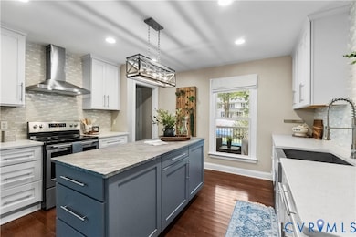 Kitchen with tasteful backsplash, stainless steel electric range oven, wall chimney exhaust hood, white cabinets, and recessed lighting