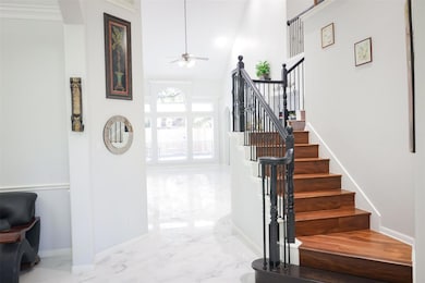 Staircase with marble tiled flooring, a ceiling fan, and a high ceiling