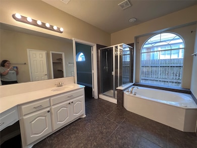 Bathroom featuring a bath, vanity, a shower stall, a walk in closet, and dark tile patterned floors