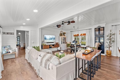 Living area featuring recessed lighting, wood finished floors, crown molding, a ceiling fan, and a chandelier