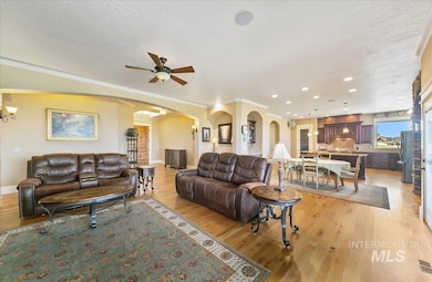 Living area featuring arched walkways, light wood-style floors, recessed lighting, ceiling fan, and a textured ceiling