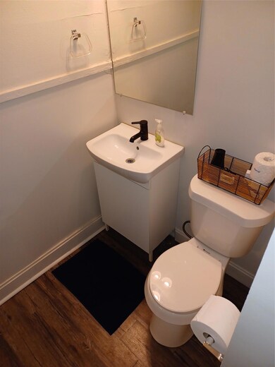 Half bath with wood finished floors, toilet, vani