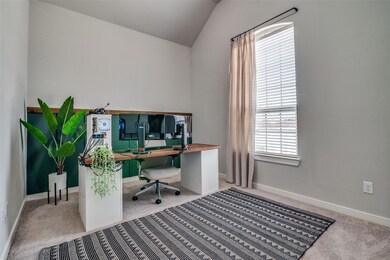 Home office with lofted ceiling, and carpet flooring