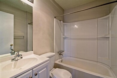 Bathroom featuring a textured wall, toilet, vanit