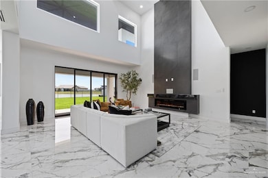 Living area with a towering ceiling, marble tiled flooring, a fireplace, and recessed lighting