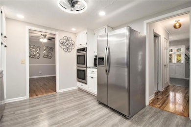 Kitchen with stainless steel appliances, white cabinets, light wood finished floors, ceiling fan, and recessed lighting