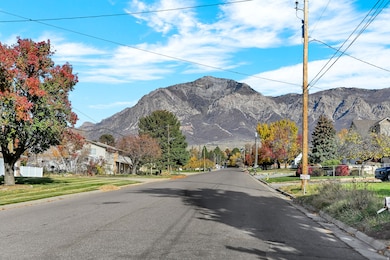 View of asphalt road featuring curbs, a mountain view, and a residential view