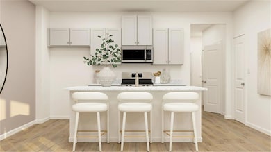 Kitchen featuring a breakfast bar area, light hardwood / wood-style flooring, an island with sink, and white range with gas stovetop