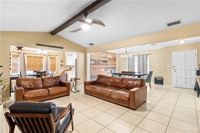 Tiled living room featuring a wealth of natural light, lofted ceiling with beams, and ceiling fan with notable chandelier