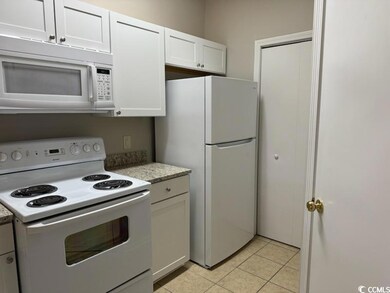 Kitchen with white appliances, white cabinetry, an