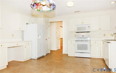 Kitchen featuring white appliances, light countertops, and white cabinetry