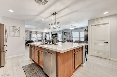 Kitchen featuring open floor plan, recessed lighting, appliances with stainless steel finishes, plenty of natural light, and brown cabinetry