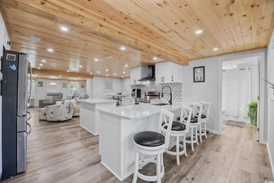 Kitchen with a kitchen island, wooden ceiling, white cabinetry, a kitchen breakfast bar, and stainless steel appliances