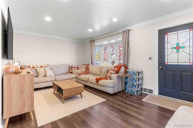 Living room with dark wood-style flooring, recessed lighting, and crown molding