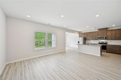 Kitchen with open floor plan, stainless steel appliances, decorative backsplash, light wood-style flooring, and recessed lighting