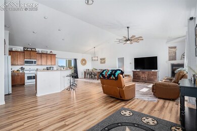 Living room featuring light wood-style floors, high vaulted ceiling, ceiling fan, and a glass covered fireplace