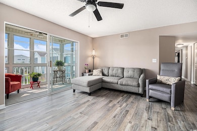 Living room featuring newly installed LVP flooring, a textured ceiling, and a ceiling fan