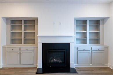 Unfurnished living room featuring light wood finished floors and a glass covered fireplace