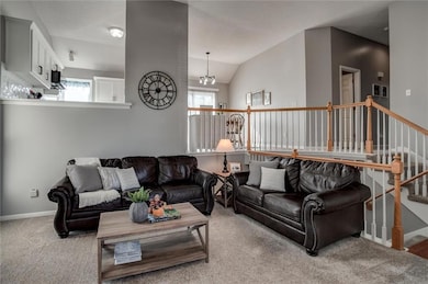 Carpeted living area featuring vaulted ceiling and a chandelier
