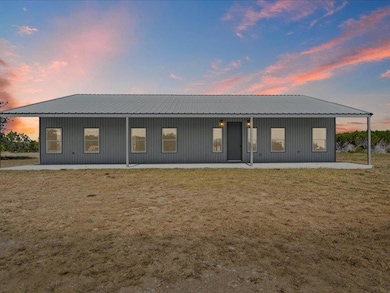 Back of house with covered porch and a metal roof