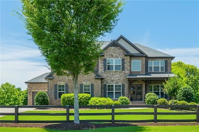 Craftsman inspired home featuring a fenced front yard, a garage, and stone siding