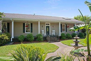 Photo. Full length porch offers views of lush gard