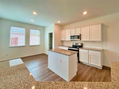 Kitchen featuring dark hardwood / wood-style floors, light stone countertops, a center island, white cabinetry, and appliances with stainless steel finishes