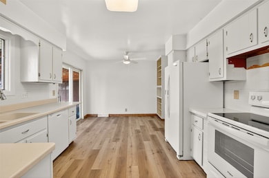 Kitchen with backsplash, white appliances, light countertops, and light wood-type flooring