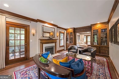 Living area with ornamental molding, a fireplace with flush hearth, wood finished floors, and recessed lighting
